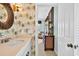 Charming bathroom with palm wallpaper, round mirror, marble countertops, connecting to bedroom at 1510 North Shore Dr, Sunset Beach, NC 28468