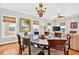 Bright dining room with chandelier, glass table, wood floors, and a view into the living room at 1510 North Shore Dr, Sunset Beach, NC 28468
