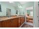 Bathroom with double sinks, granite countertops, warm wood cabinets, and a view of the bedroom at 1907 Enclave Ln. # 1907, North Myrtle Beach, SC 29582