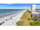 Aerial view of the sandy beach, ocean, and the condo complex with nearby trees and foliage at 208 N Ocean Blvd. # 226, North Myrtle Beach, SC 29582