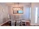Dining room with glass table, upholstered chairs, and modern hanging light fixture at 219 Birdie Way, Longs, SC 29568