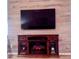 Cozy fireplace with wooden mantel and large television mounted above on light wood paneled wall at 219 Birdie Way, Longs, SC 29568