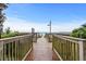 Wooden boardwalk leading to a sandy beach and the ocean, lined with lush vegetation at 2504 N Ocean Blvd. # 1936, Myrtle Beach, SC 29577