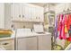 Bright laundry room with white washer, dryer, cabinets, and a clothes rack at 424 Villa Woods Dr., Myrtle Beach, SC 29579