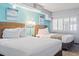 Bright bedroom with two queen beds, beach artwork, and white shuttered windows at 4800 S Ocean Blvd. # 1008, North Myrtle Beach, SC 29582