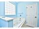 A bright bathroom features a white bathtub with tile surround and glass block window at 501 Painted Duck Ct., Myrtle Beach, SC 29588