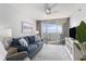Living room features blue sofa, area rug, TV and sliding glass door access to balcony at 5523 N Ocean Blvd. # 1505, Myrtle Beach, SC 29577