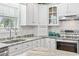 Bright kitchen features white cabinets, granite countertops, and stainless steel appliances at 709 Triple Oak Ln., Garden City Beach, SC 29576