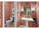 Elegant powder room featuring patterned wallpaper, pedestal sink, and decorative mirror at 81 Prestwick Dr., Pawleys Island, SC 29585