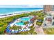 Gorgeous aerial shot of a resort pool with palm trees, lounge chairs, beach access, and blue umbrellas at 8148 Living Tide Dr., Myrtle Beach, SC 29572