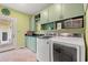 Functional laundry room with green cabinets, a sink, washer, and dryer at 89 Cameron Ct., Pawleys Island, SC 29585