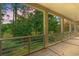 View from covered patio with metal railing overlooking lush green lawn and wooded area, offering serene outdoor enjoyment at 89 Cameron Ct., Pawleys Island, SC 29585