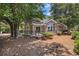Charming brick home featuring large arched windows, a fenced-in patio, and mature trees providing ample shade at 90 Old Carriage Ln., Pawleys Island, SC 29585