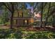 Charming brick home with green shutters nestled among mature trees in a lush, green lawn at 90 Old Carriage Ln., Pawleys Island, SC 29585