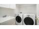 Clean laundry room equipped with modern washer, dryer, a utility sink and storage at 90 Old Carriage Ln., Pawleys Island, SC 29585