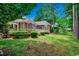 Expansive backyard with a brick house, lush greenery, a well-manicured lawn, and a charming patio area at 911 Tilghman Forest Dr., North Myrtle Beach, SC 29582