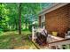 Cozy outdoor patio space with a grill, bench seating, and a view of the lush backyard and mature trees at 911 Tilghman Forest Dr., North Myrtle Beach, SC 29582