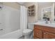 Well-lit bathroom with a shower and tub combo, a wooden storage shelf, and a wood-stained vanity at 1011 Sable Palm Way, Surfside Beach, SC 29575