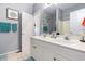 Bright bathroom featuring a dual sink vanity, large mirror, soft gray walls, and decorative art, and a glimpse of the shower area at 106 Scotch Broom Dr. # 105, Little River, SC 29566
