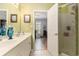 Bright bathroom featuring a dual sink vanity, a walk-in shower, light green walls, and access to bedroom at 106 Scotch Broom Dr. # 105, Little River, SC 29566