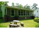 Green home showcasing a screened-in back porch, patio seating, and beautiful landscaping at 116 Capt Anthony White Ln., Georgetown, SC 29440