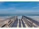 Wooden boardwalk leading to a sandy beach and the ocean under a clear blue sky with scattered clouds at 118 Goodson Loop, Pawleys Island, SC 29585