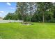 Lush backyard featuring a well-maintained lawn, white fence, and a charming stone fire pit area with seating at 120 River Country Dr., Conway, SC 29526