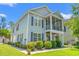 Two-story home with well-manicured lawn, lush landscaping, screened-in porch, and blue siding at 1415 Powhaton Dr., Myrtle Beach, SC 29577