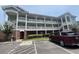 Three story condo building with brick facade and covered outdoor hallways, light green siding, and a maroon Kia van at 1514 Lanterns Rest Dr. # 103, Myrtle Beach, SC 29579