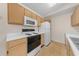 Bright kitchen with white appliances, wood cabinetry, and tile flooring for easy maintenance at 1931 Bent Grass Dr. # H, Surfside Beach, SC 29575