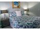 Charming bedroom with coastal-themed bedding, bedside lamps, and decorative beach painting at 2001 S Ocean Blvd. S # 1013, Myrtle Beach, SC 29577