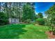 Spacious backyard with a storage shed, lush green grass, and mature trees at 220 Gateway Dr., Little River, SC 29566