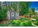 Backyard showing shed with green grass, mature trees, and landscaping at 220 Gateway Dr., Little River, SC 29566
