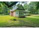 Side view of a green home showcasing its brick accents and lush, green lawn at 309 Otter Run Rd., Pawleys Island, SC 29585