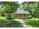 Charming green home featuring a welcoming front porch and well-manicured lawn and landscaping at 309 Otter Run Rd., Pawleys Island, SC 29585