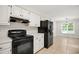 Kitchen with dark stove and refrigerator contrasted with white cabinets and a tile floor at 309 Otter Run Rd., Pawleys Island, SC 29585