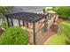 View of the backyard with an outdoor kitchen under a pergola, a brick patio and lush greenery at 312 Caldera Ct., Murrells Inlet, SC 29576