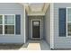 Close-up of a home's entrance with a dark front door framed by light gray siding and blue shutters at 437 Shallow Cove Dr., Conway, SC 29527
