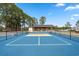 Well-maintained tennis court with blue surface, surrounded by trees, and greenery, enhancing the outdoor recreational space at 4709 National Dr., Myrtle Beach, SC 29579