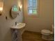 Bright, farmhouse bathroom with wood plank walls, pedestal sink, round mirror and decorative lighting at 4719 National Dr., Myrtle Beach, SC 29579