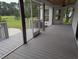 Screened-in porch with grey wood flooring, a ceiling fan, and views of the spacious, green backyard at 4719 National Dr., Myrtle Beach, SC 29579