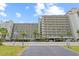Large tan condo building with multiple stories, palm trees, and parking at 4719 S Ocean Blvd. # 108, North Myrtle Beach, SC 29582