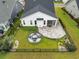 This aerial shows a backyard with a paver patio, firepit, manicured lawn, and black metal fencing at 5087 Sundrop Ln., Little River, SC 29566