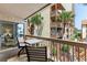Balcony seating area with a view of lush greenery, palm trees, and a glimpse of the ocean at 5515 N Ocean Blvd. N # 206, Myrtle Beach, SC 29577