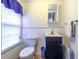 Compact bathroom featuring a dark vanity with a white sink, toilet, and small mirror at 609 3Rd Ave. N, Myrtle Beach, SC 29577