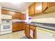Well-lit kitchen with wood cabinets, white appliances, and tiled floors providing a practical cooking space at 609 3Rd Ave. N, Myrtle Beach, SC 29577