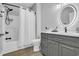 Updated bathroom with a shower and tub combination, sleek gray vanity, and a modern, round, lighted mirror at 7356 Johnson Shortcut Rd., Conway, SC 29527