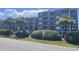 Low angle view of a well-kept condo building with palm trees and fresh landscaping on a sunny day at 812 S Ocean Blvd. # B-3, Surfside Beach, SC 29575