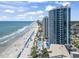 Aerial view of condominiums along a beach with the ocean, people, and pools on a sunny day at 107 S Ocean Blvd. # 503, Myrtle Beach, SC 29577