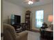 Bright living room with a ceiling fan, large window, comfortable seating, and a bookshelf filled with books and decor at 1307 Carolina Wren Ln., Murrells Inlet, SC 29576